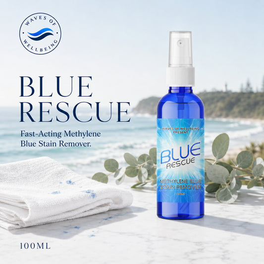 Waves of Wellbeing Blue Rescue 100ml — fast-acting Methylene Blue stain remover, shown beside a stained towel on marble with a coastal background