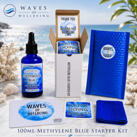 Waves of Wellbeing 50ml Methylene Blue Starter Kit — bottle, bubble mailer, spill mat, microfibre cloth and welcome cards on marble with coastal background
